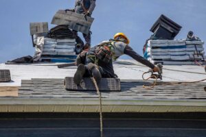 A person in work gloves carefully climbing a ladder beside a house with a visible sloped roof.